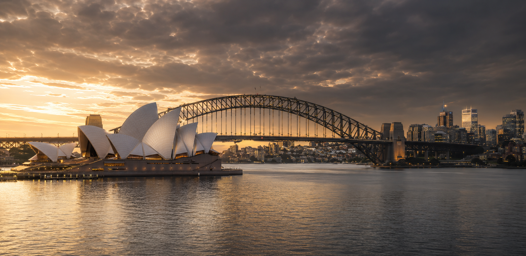 Sydney Opera House and Harbour Bridge at sunset with golden skies